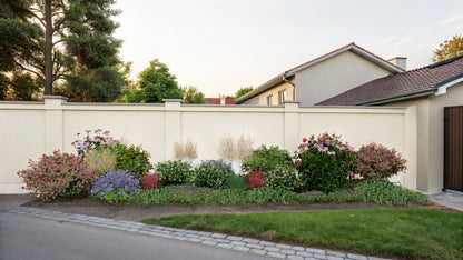 Summer view of the composition showing the varied plant heights and the structure of the arrangement in front of a fence wall